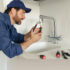 Plumber in Memphis adjusting a sink faucet with a tool.