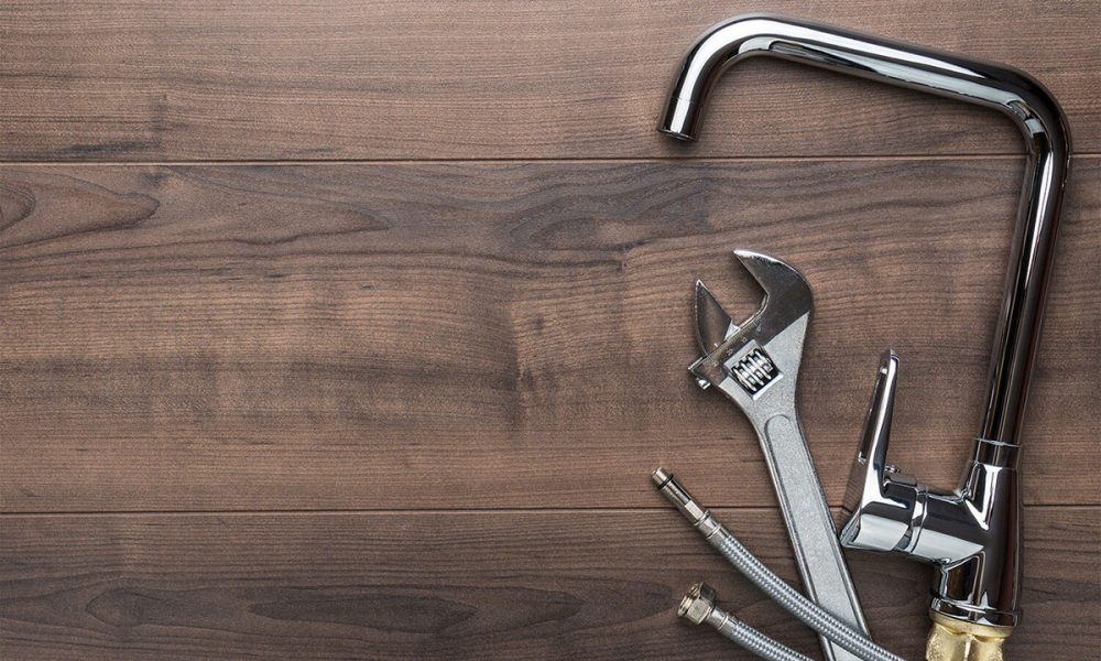 sink faucet, wrench and water line on a dark wood floor